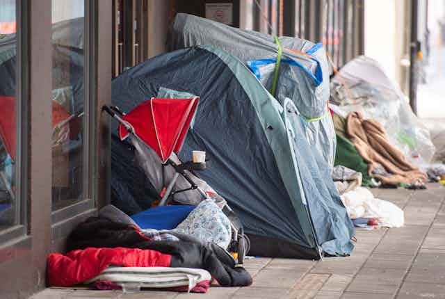 Homeless tents and a stroller next to department store doors