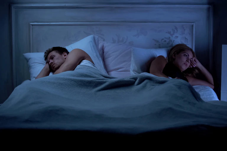 a couple on the edges of a bed