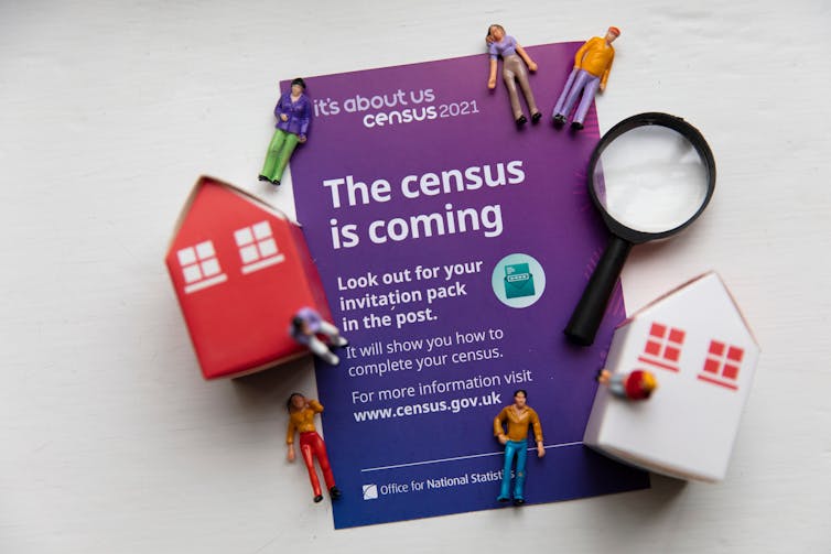 A census 2021 form currounded by models of people, houses, and a magnifying glass