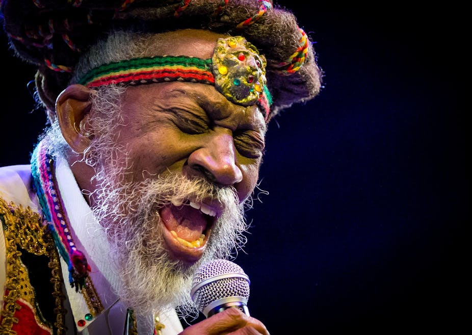 Bunny Wailer singing into microphone with rastafarian headband around his forehead