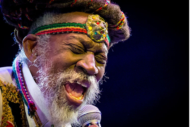 Bunny Wailer singing into microphone with rastafarian headband around his forehead
