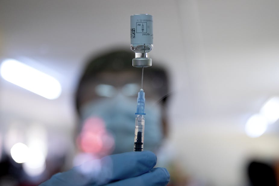 Vial of Johnson & Johnson vaccine balances on a syringe