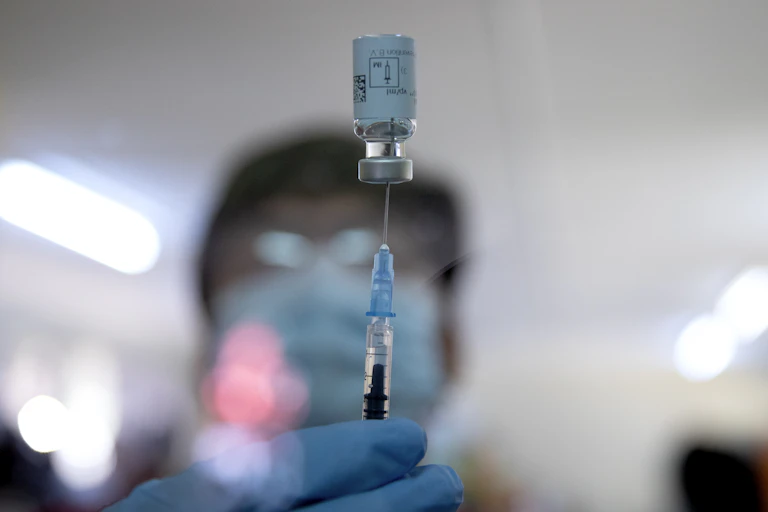 Vial of Johnson & Johnson vaccine balances on a syringe