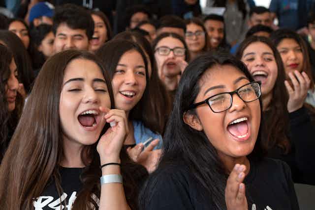 A crowd of high school students clap and cheer