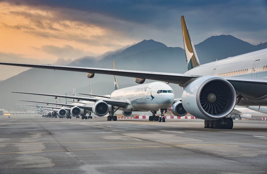 A row of aeroplanes on the tarmac with mountain behind. 