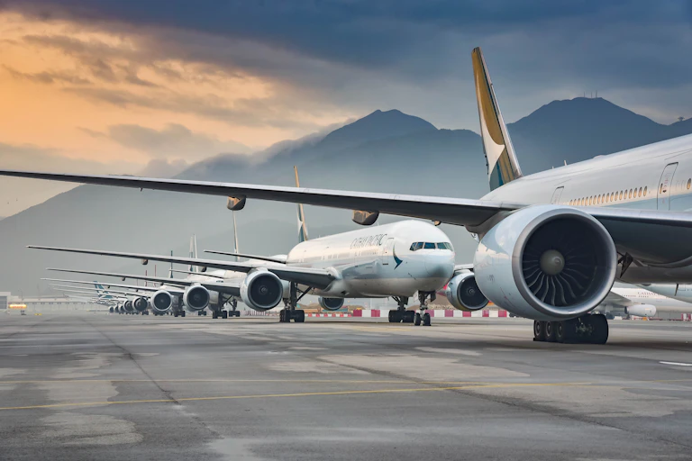 A row of aeroplanes on the tarmac with mountain behind.