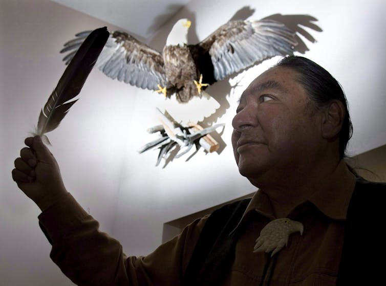 Elijah Harper holds up an eagle feather.