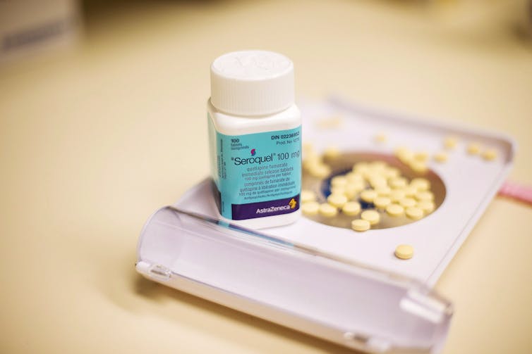 A bottle of anti-psychotic medication beside a tray of pills.