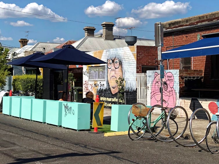 pop-up eating space with shade umbrellas and bike stand outside a cafe