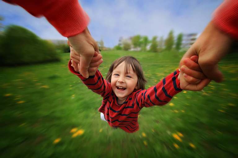 Parents spinning child around by the hands