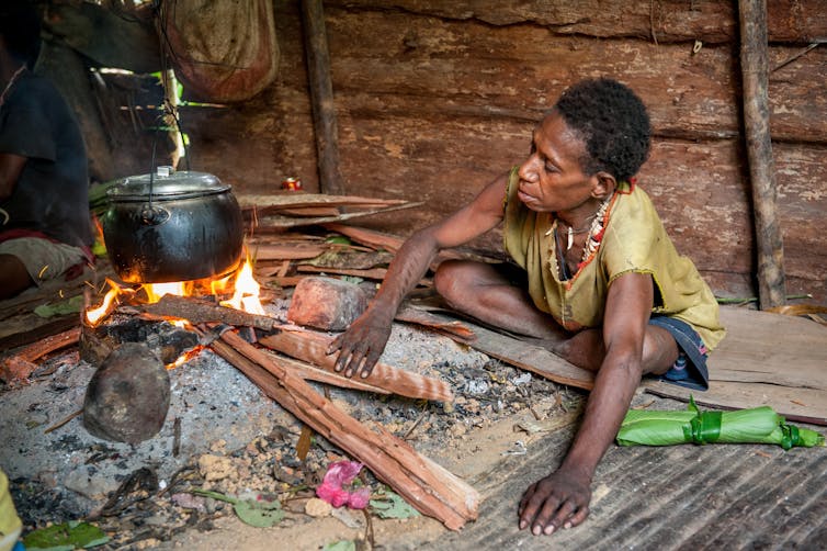 A PNG resident cooks over a fire
