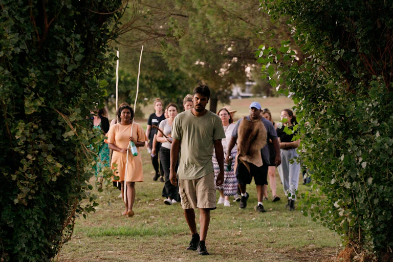 Man leads walkers through trees.