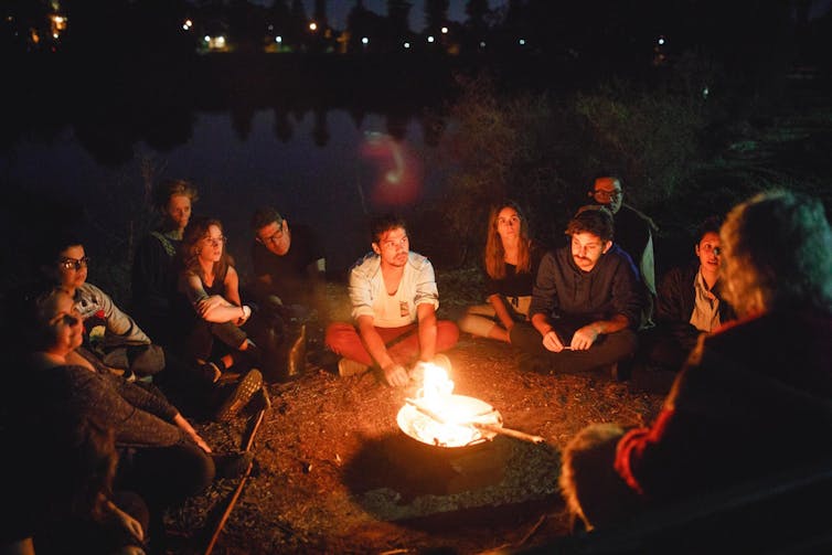 people sitting around campfire
