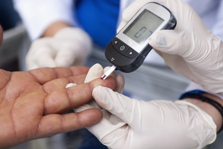 Gloved hands holding an electronic device which is touching a drop of blood on another person's finger