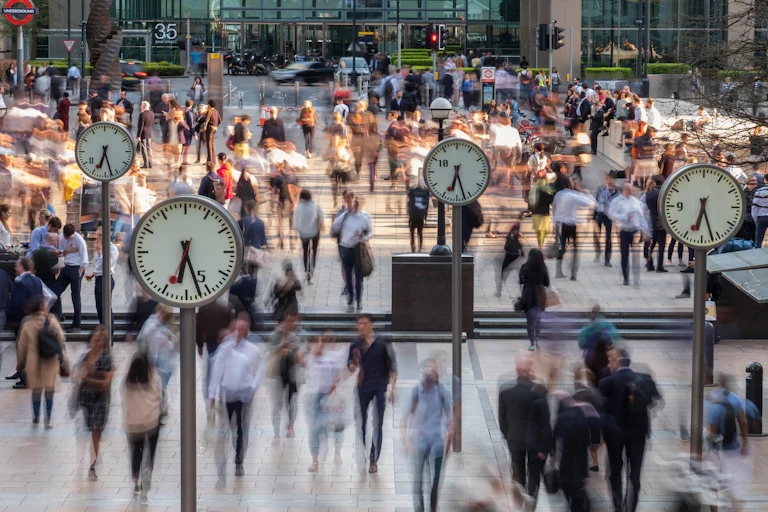 Blurred people walking through Canary Wharf with clocks in the foreground