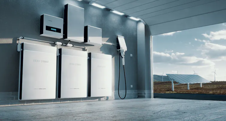 A concept image of a home energy storage system with solar panels and wind turbines outside.