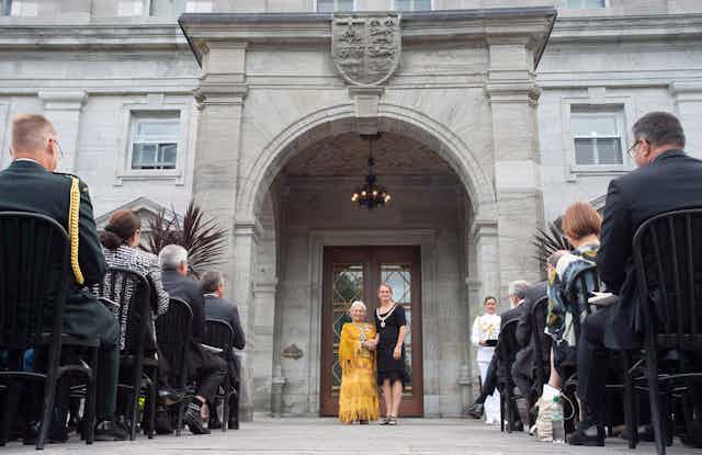 Julie Payette and Jeanette Corbiere, wearing a yellow dress, stand outside Rideau Hall.