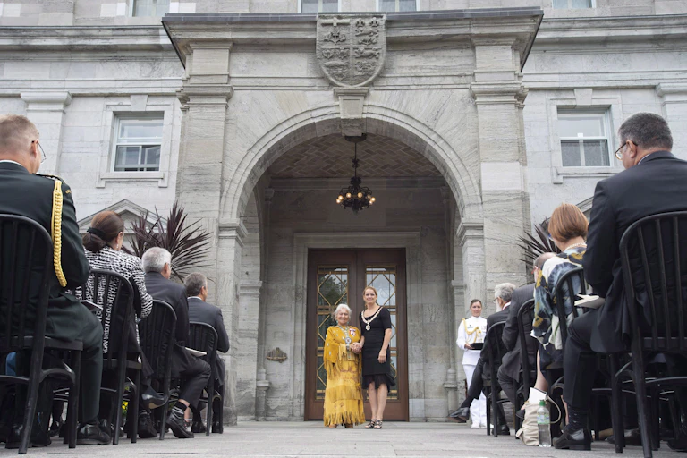 Julie Payette and Jeanette Corbiere, wearing a yellow dress, stand outside Rideau Hall.