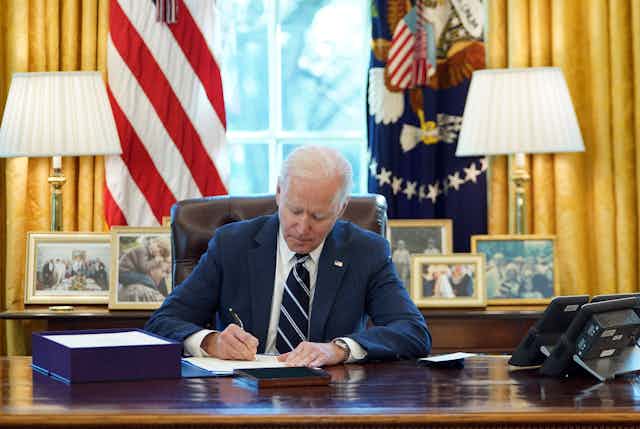 President Joe Biden at his desk in the Oval Office