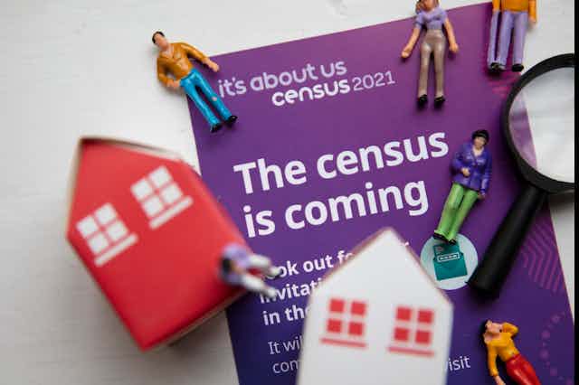 Figurines of house and people on top of census 2021 information booklet