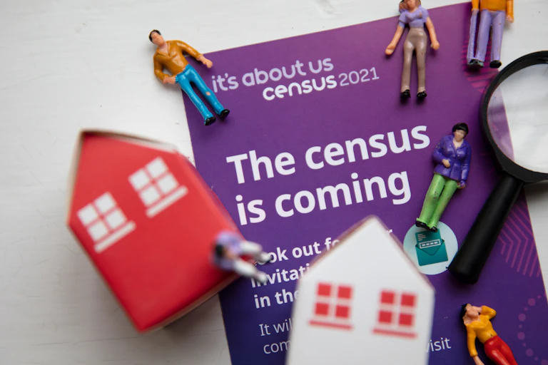 Figurines of house and people on top of census 2021 information booklet
