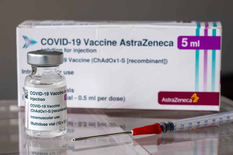 A vial of AstraZeneca vaccine, a needle and a box.