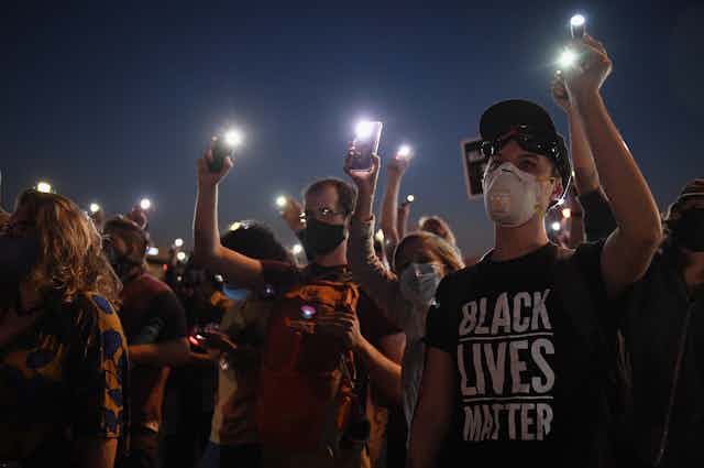 Demonstrators hold up cell phones during a protest
