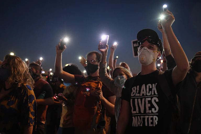 Demonstrators hold up cell phones during a protest