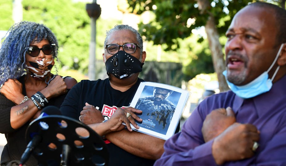 A man holds a picture of Chadwick Boseman.