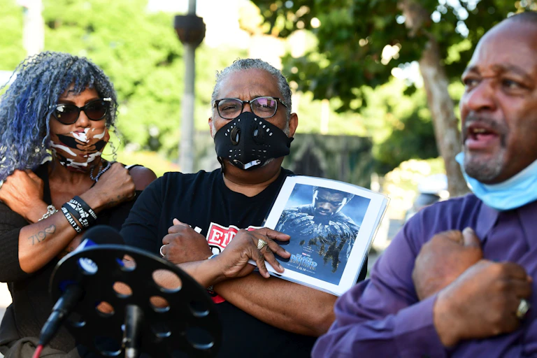 A man holds a picture of Chadwick Boseman.