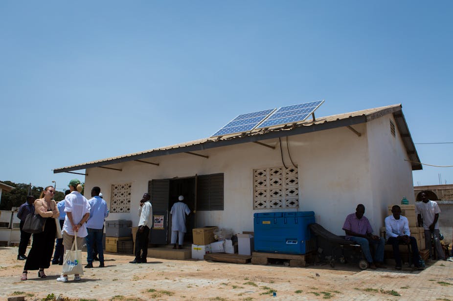 People standing in front of a small building with solar panels on its roof