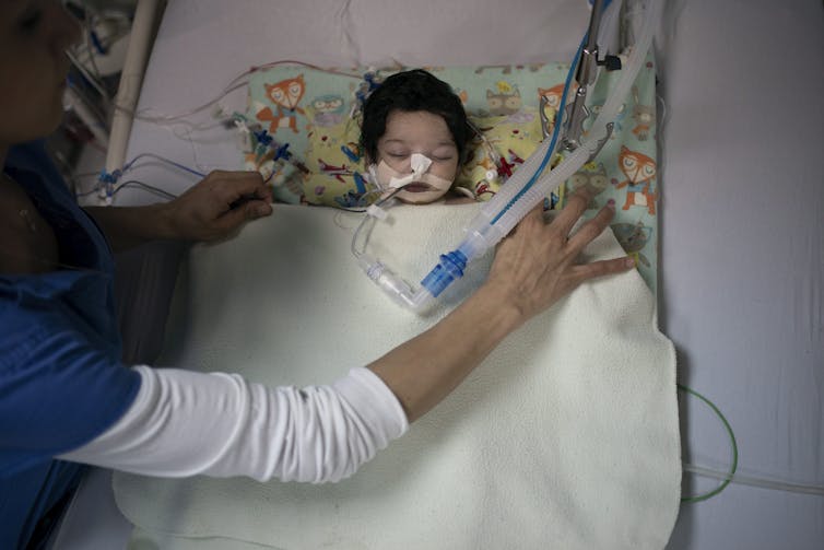 A nurse places a blanket over an infant