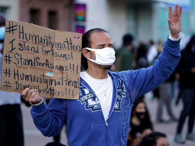 Man holds signs supporting Asian people
