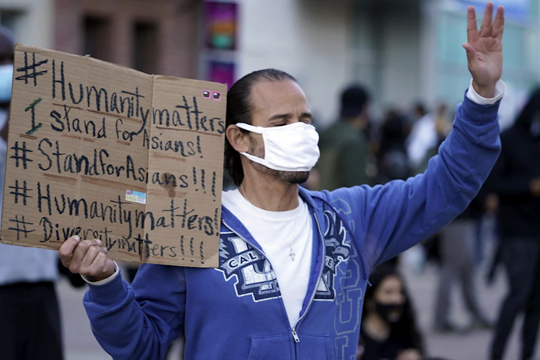 Man holds signs supporting Asian people