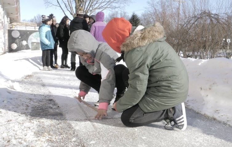 Kids work together on sidewalk in snow