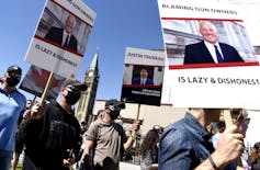 Gun owners hold signs criticizing Justin Trudeau and Bill Blair