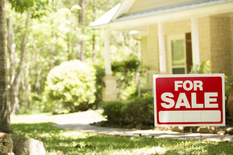 'For Sale' sign in yard of a house