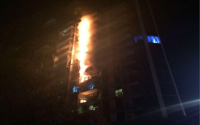 flames going up the side of an apartment building through the cladding