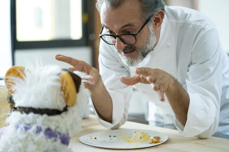 Chef talks over an empty plate to a puppet.