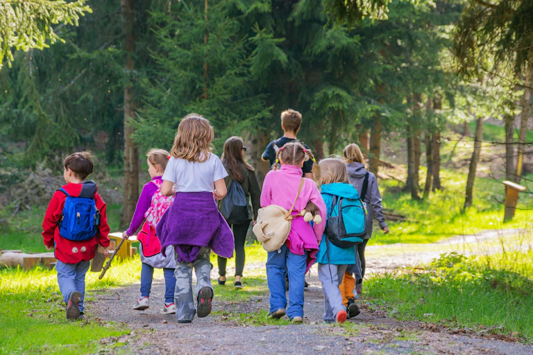 children and adult walk through forest