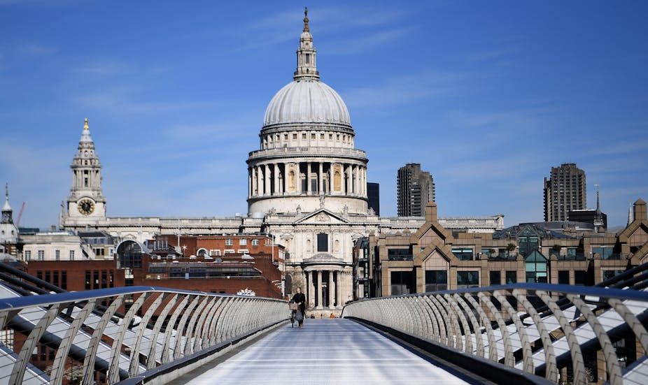 A person walks over the Milennium Bridge in front of St Paul's cathedral
