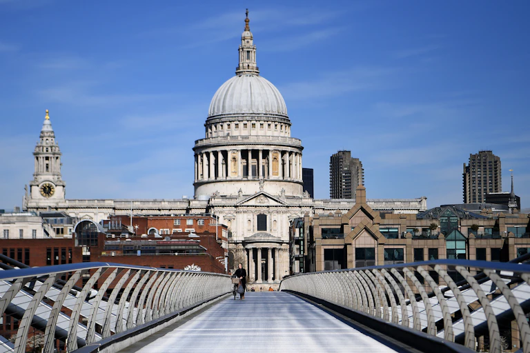 A person walks over the Milennium Bridge in front of St Paul's cathedral