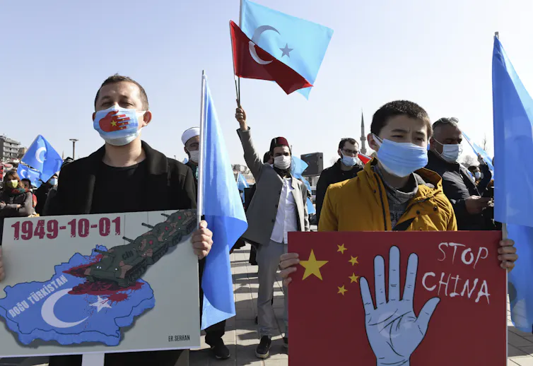 Uyghurs hold banners in a protest against China.