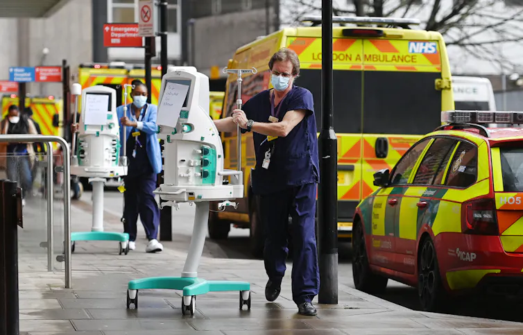 Two NHS workers wheel medical equipments into a hospital.