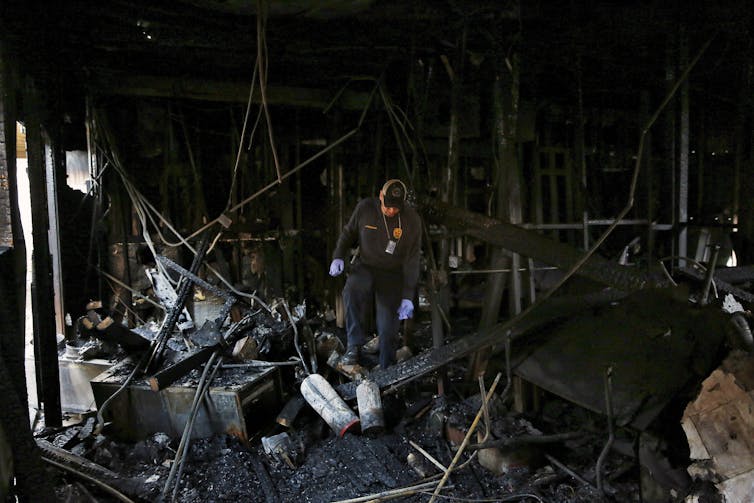 El inspector de incendios camina por las ruinas de un edificio carbonizado, mirando al suelo