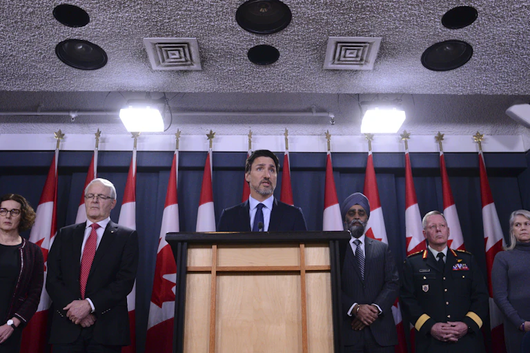 Justin Trudeau stands behind podium with ministers