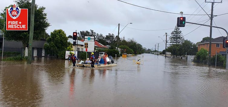 People sit in a boat while being rescued from a flood.