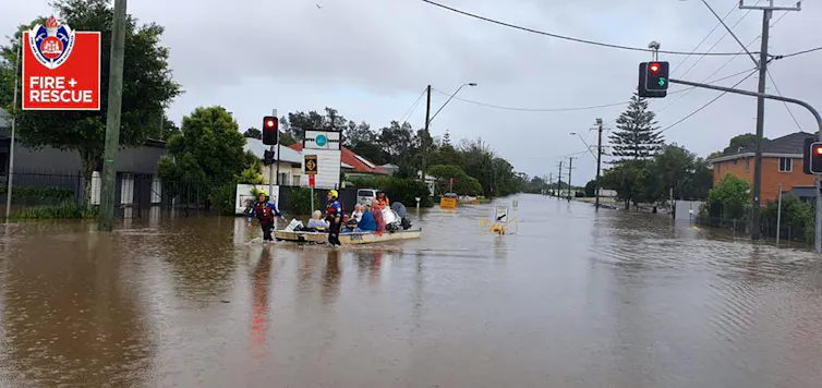 People sit in a boat while being rescued from a flood.