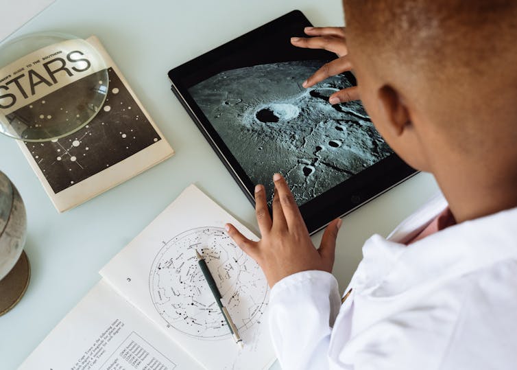 A boy with a tablet studying stars and space.