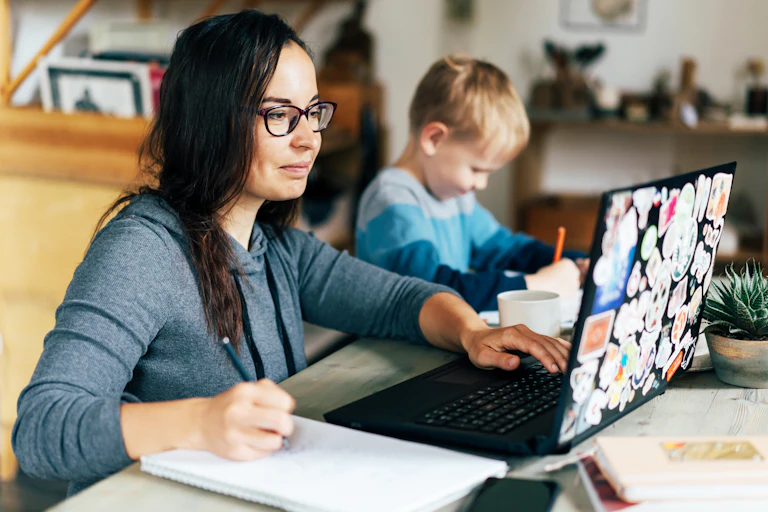 A mother doing work on a laptop.